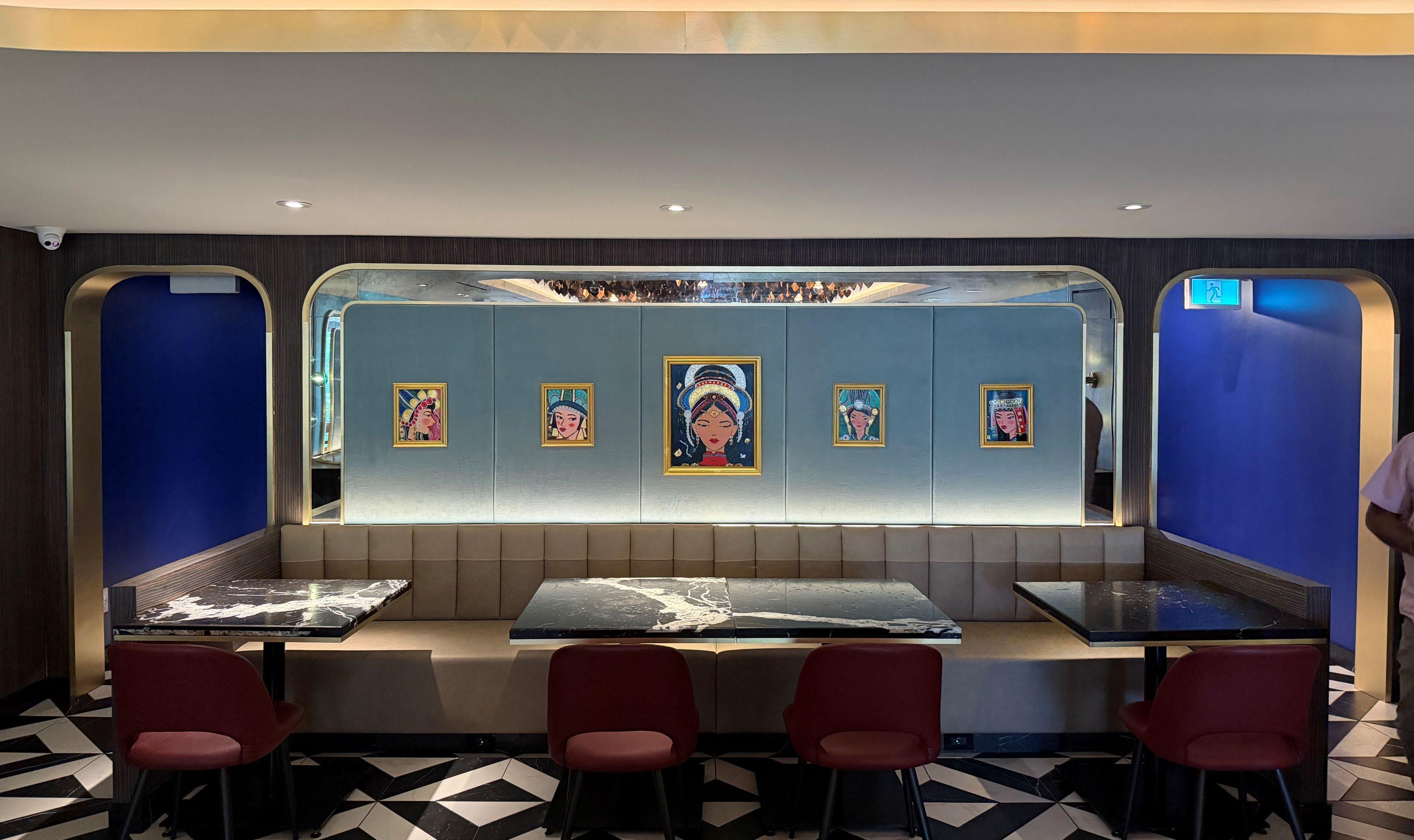 A banquette beneath a wall of portraits in gilt frames, framed by cobalt arches